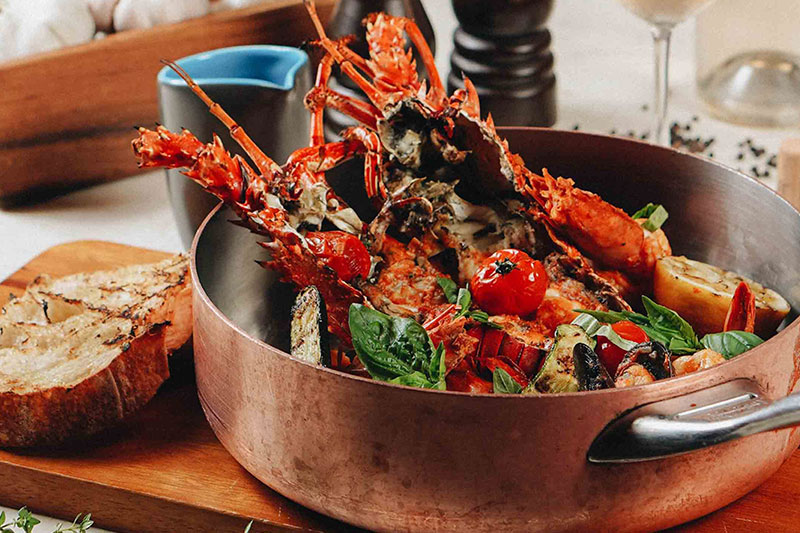 Copper pot filled with lobster, tomatoes, and bread at Prego Italian Restaurant at The Westin Resort Nusa Dua
