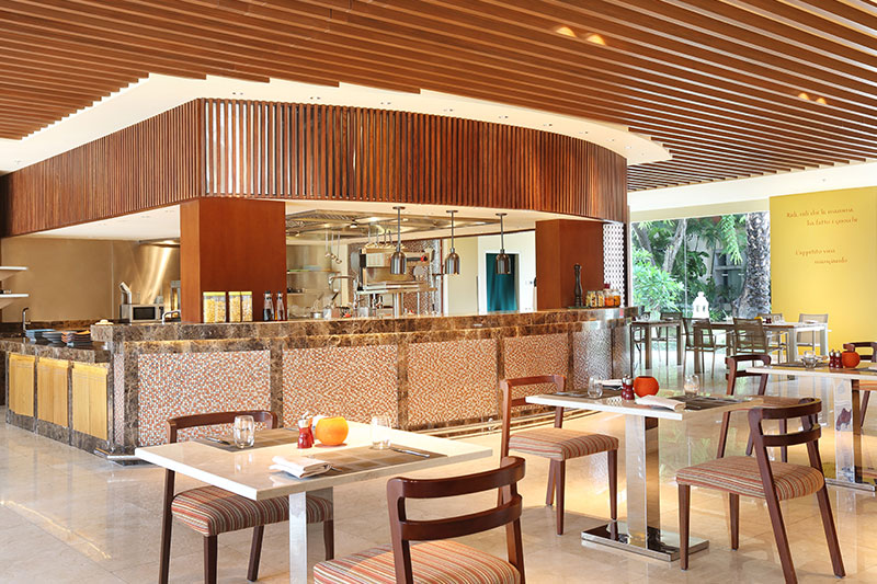 Restaurant with tables and chairs in front of an open kitchen at Prego Italian Restaurant at The Westin Resort Nusa Dua
